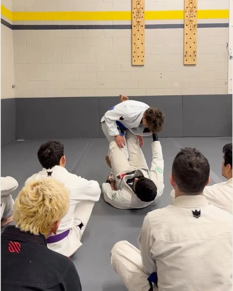 Coach demonstrating a technique on the mat while students watch