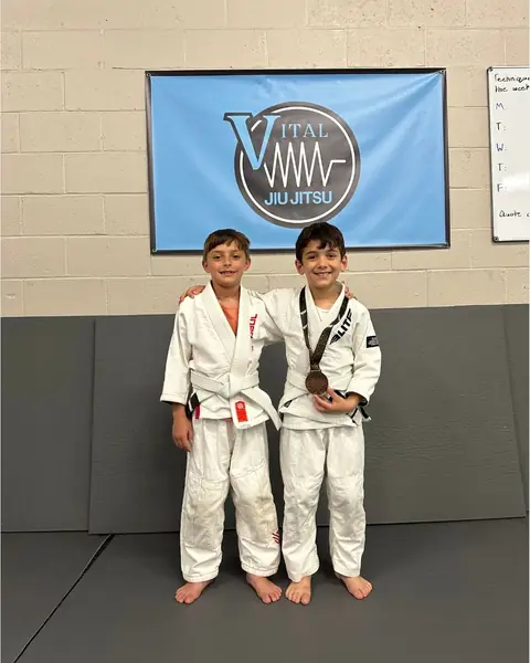 Two kids in gis wearing their medals